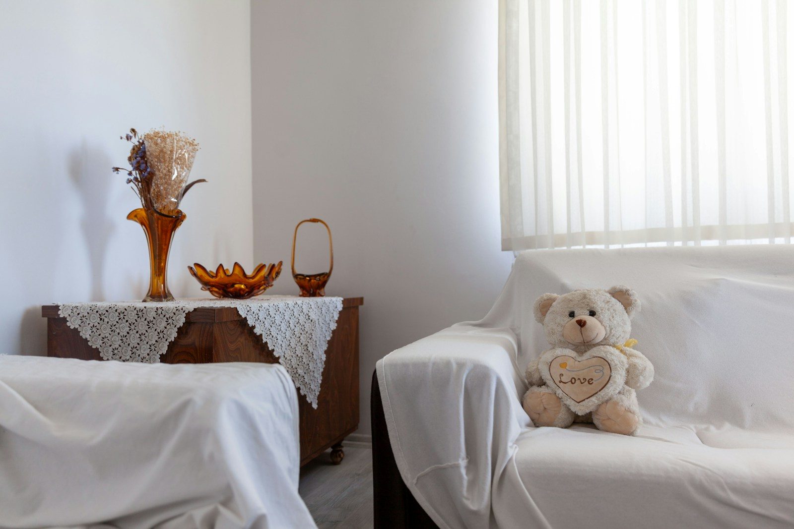 Teddy bear with heart on a white couch.