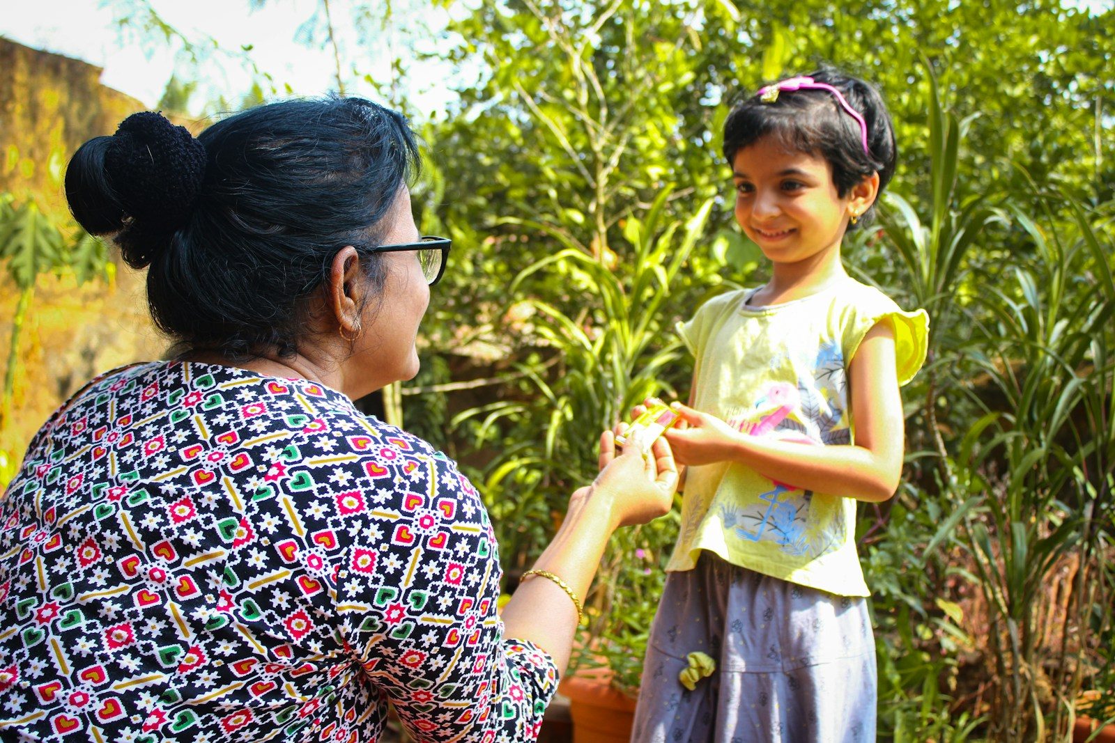 a woman holding a little girl's hand in a garden